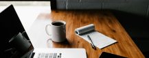 macbook-pro-white-ceramic-mugand-black-smartphone-on-table